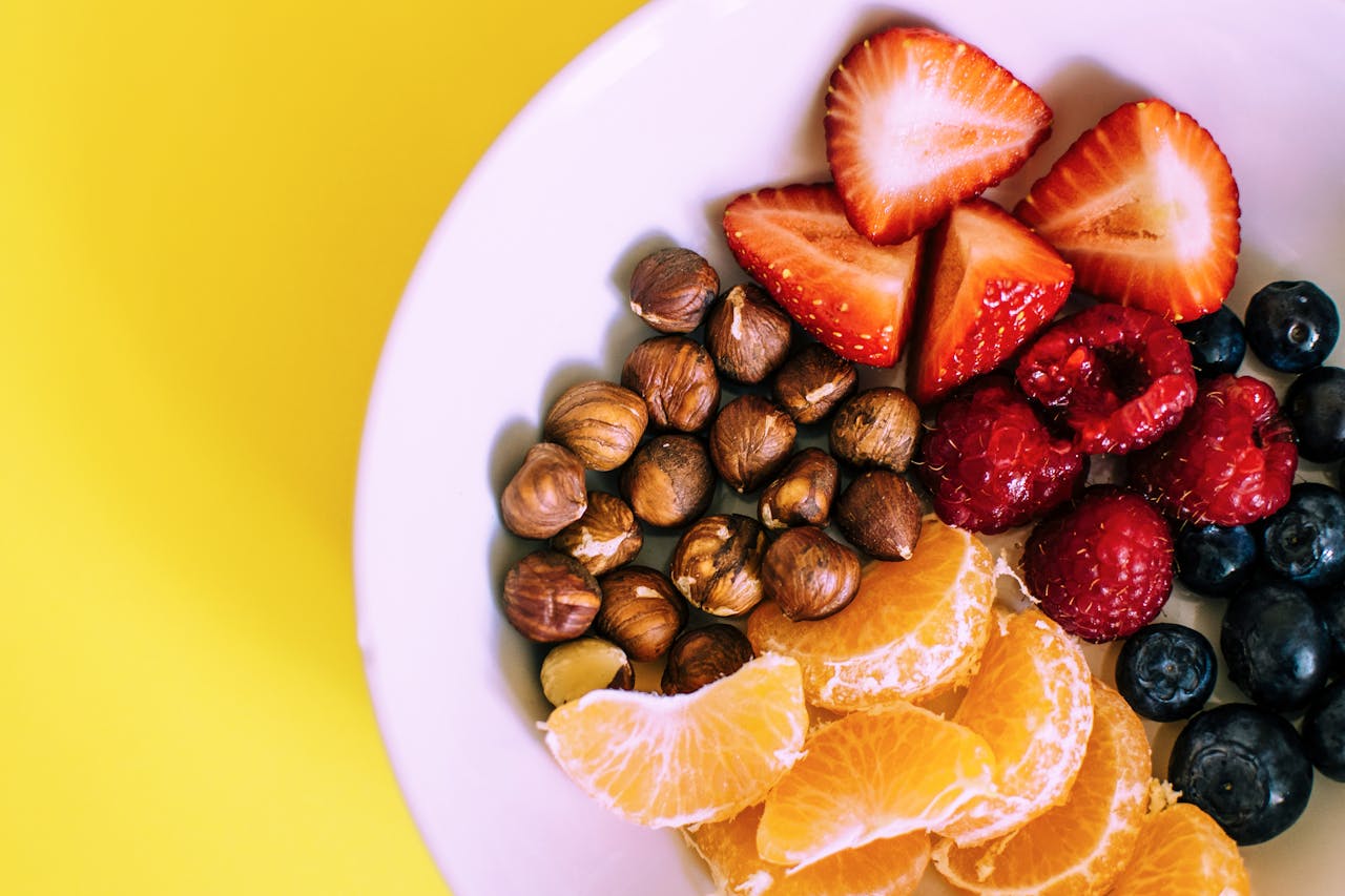 about-01 Close-up of a bowl with fresh fruits and nuts against a vibrant yellow backdrop.